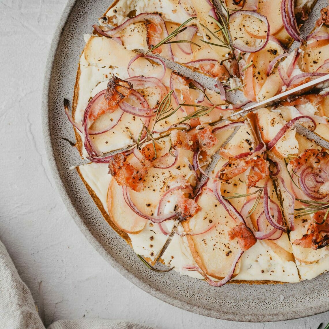 Karotten Tortilla Wrap als Flammkuchenboden Ersatz belegt mit Creme Fraîche, Speck, Äpfeln und roten Zwiebeln