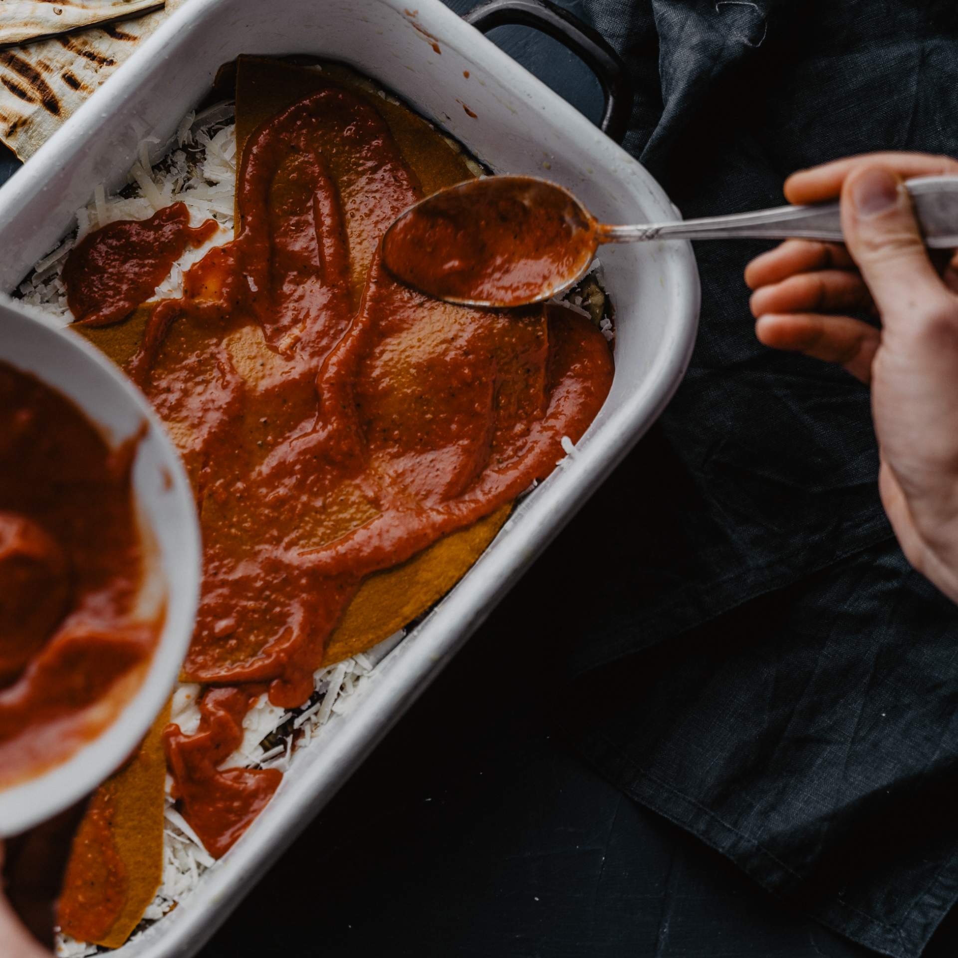 Tomatensauce wird auf Käse und Aubergine in Auflaufform gegeben