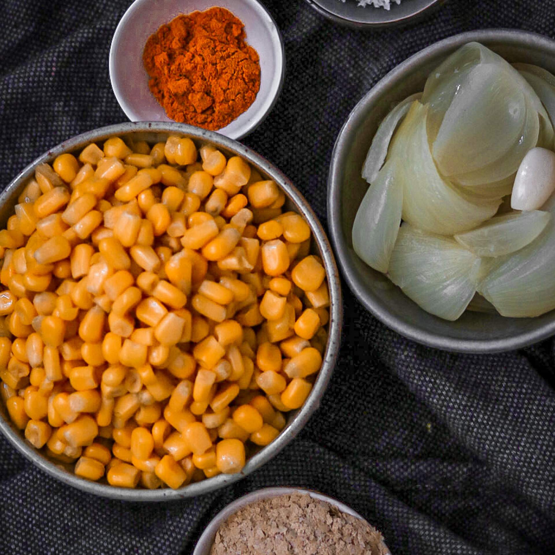 Schalen mit Mais, Gewürzen und Zwiebeln