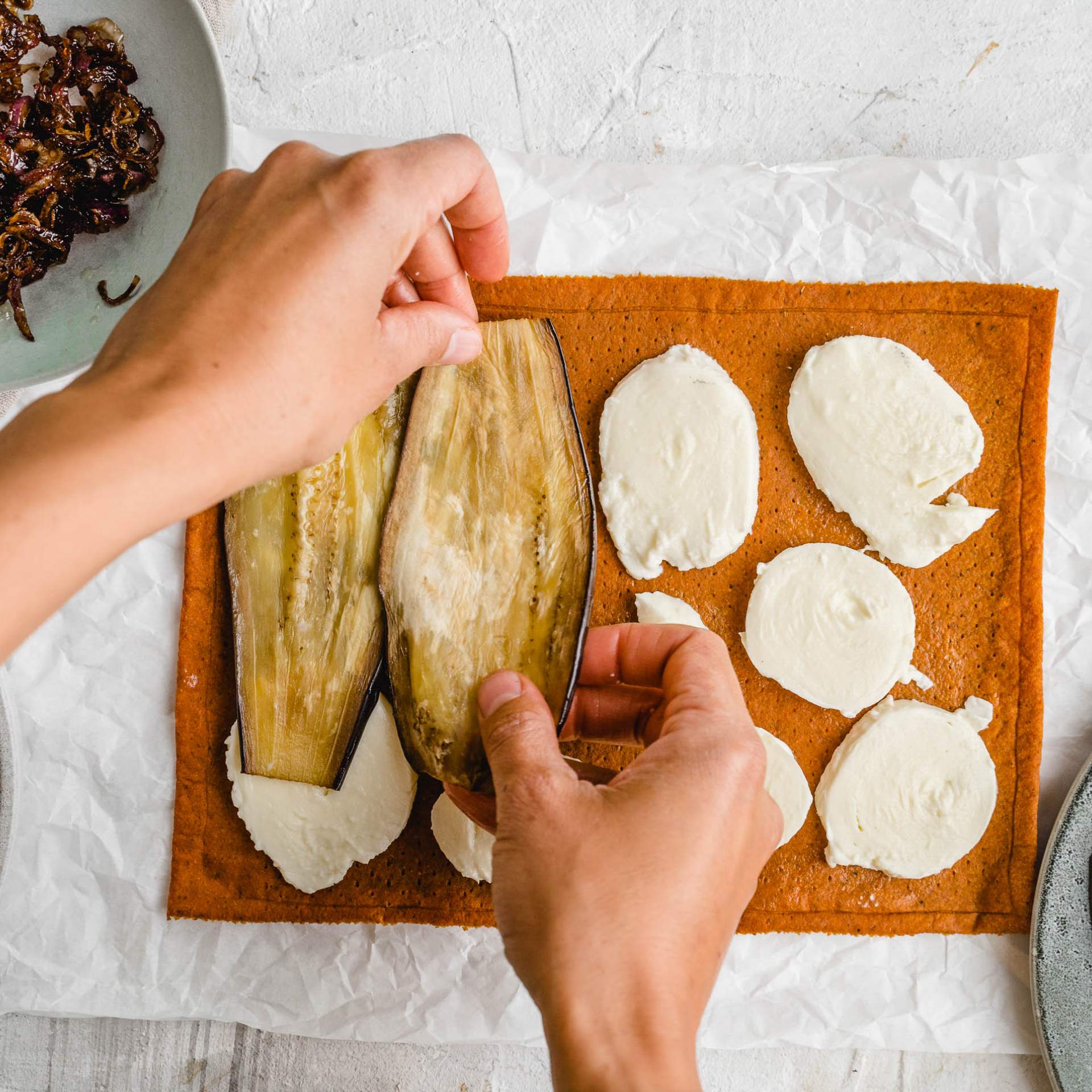Auberginenscheiben werden auf den mit Mozzarella belegten Gemüse Pizzaboden gelegt