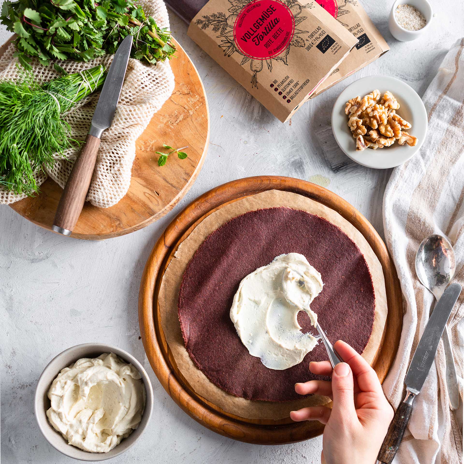 Käsecreme wird mit Löffel auf Rote Beete Tortilla Wrap gestrichen