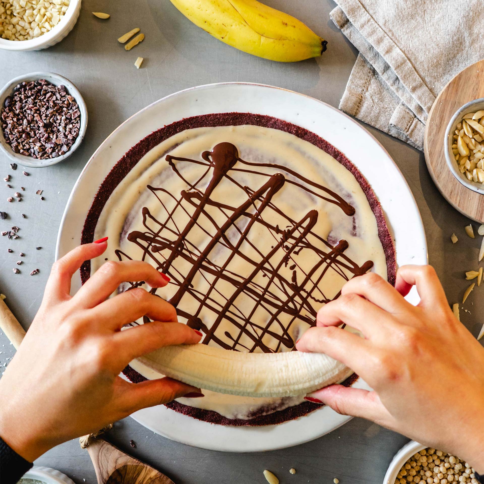 Banane wird auf Rote Beete Tortilla bestrichen mit Nussmus und Schokosauce gelegt