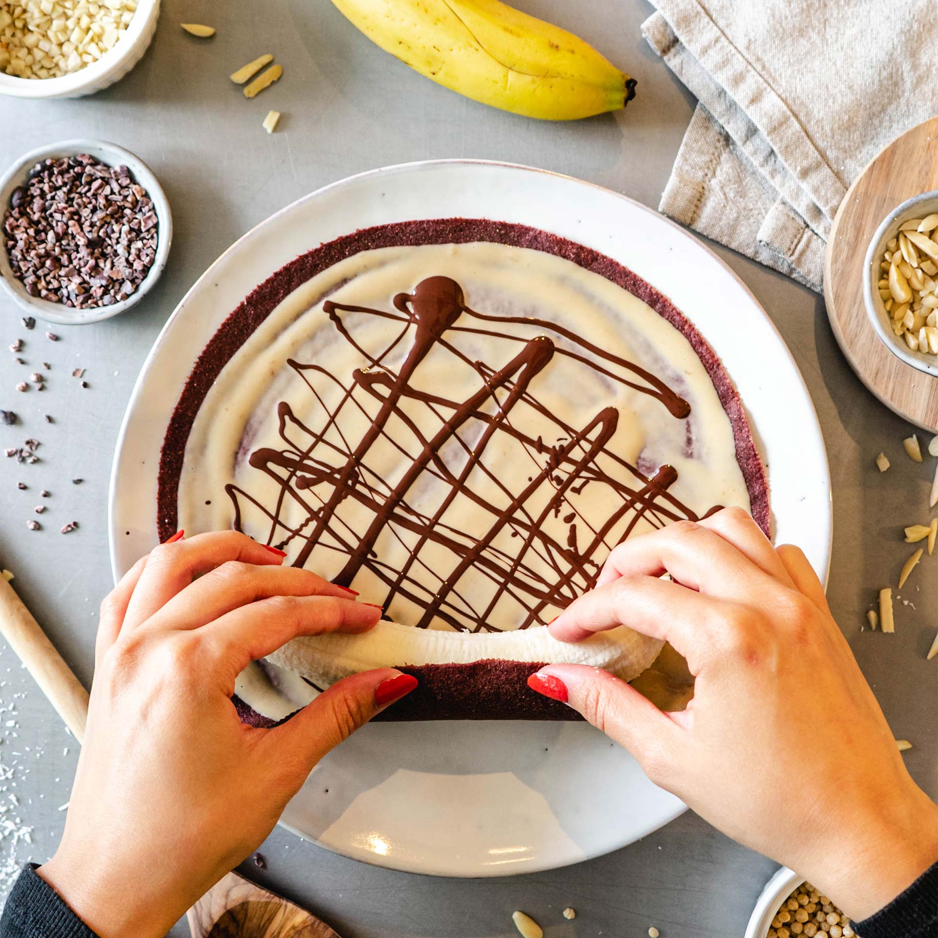 Rote Beete Tortilla bestrichen mit Nussmus und Schokosauce wird mit Banane eingerollt