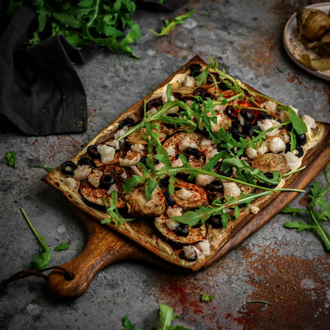 Gebackene Pizza belegt mir Artischoken, Oliven, Aubergine und Rucola