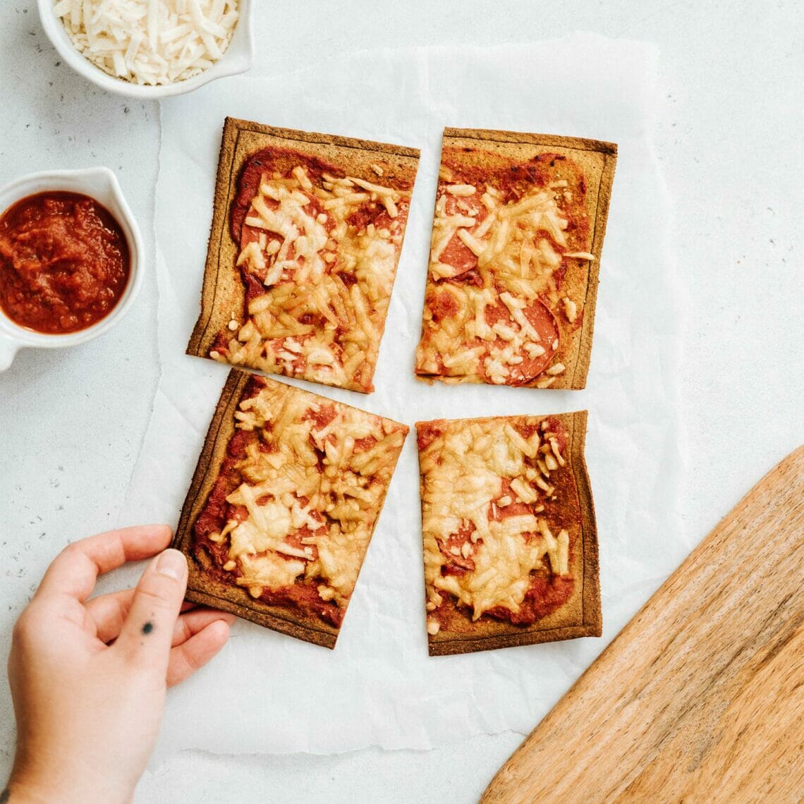 Gebackene Salami Pizza geviertelt, ein Stück wird angehoben