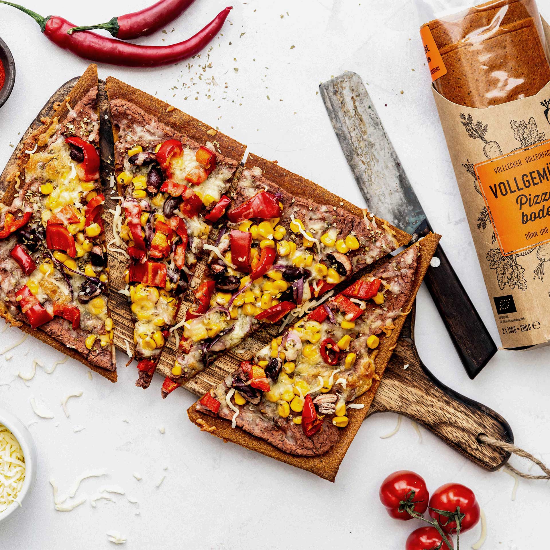 In Dreiecke geschnittene Pizza belegt mit Bohnenmus, Mais, Zwiebeln und Paprika und mit Käse überbacken