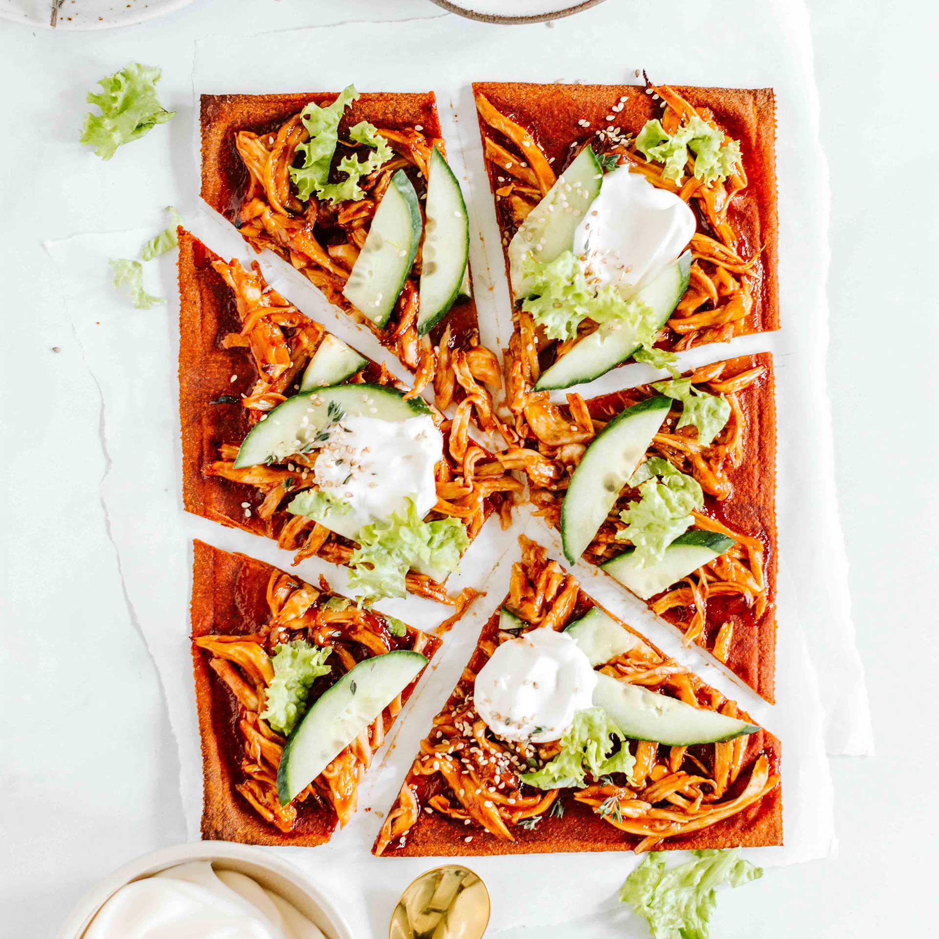 Geschnittener Pizzaboden mit Pulled Pilzen, Gurke, Sesam und Salat