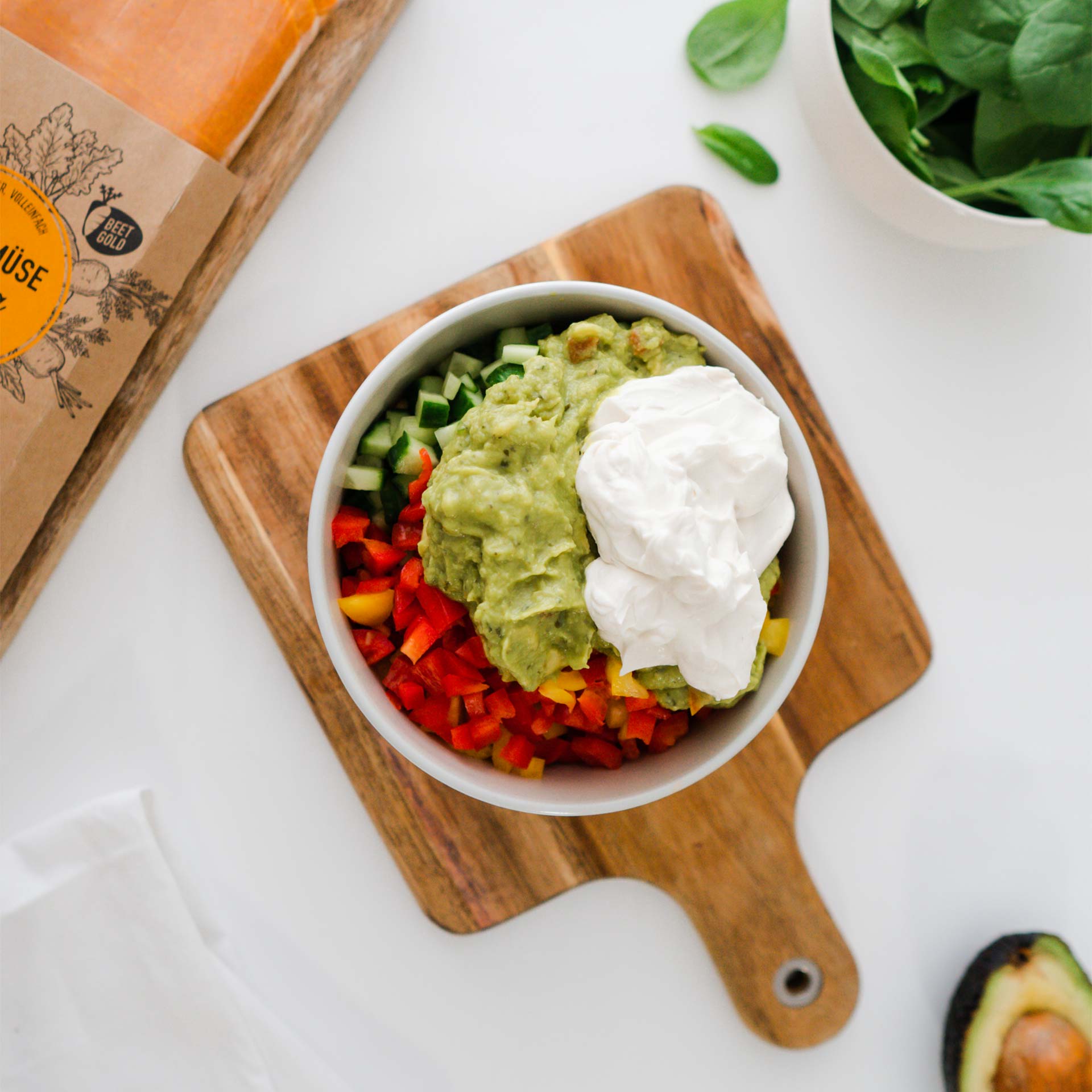 Schale mit Kichererbsen, Gurken- und Paprikawürfeln, Guacamole und Frischkäse