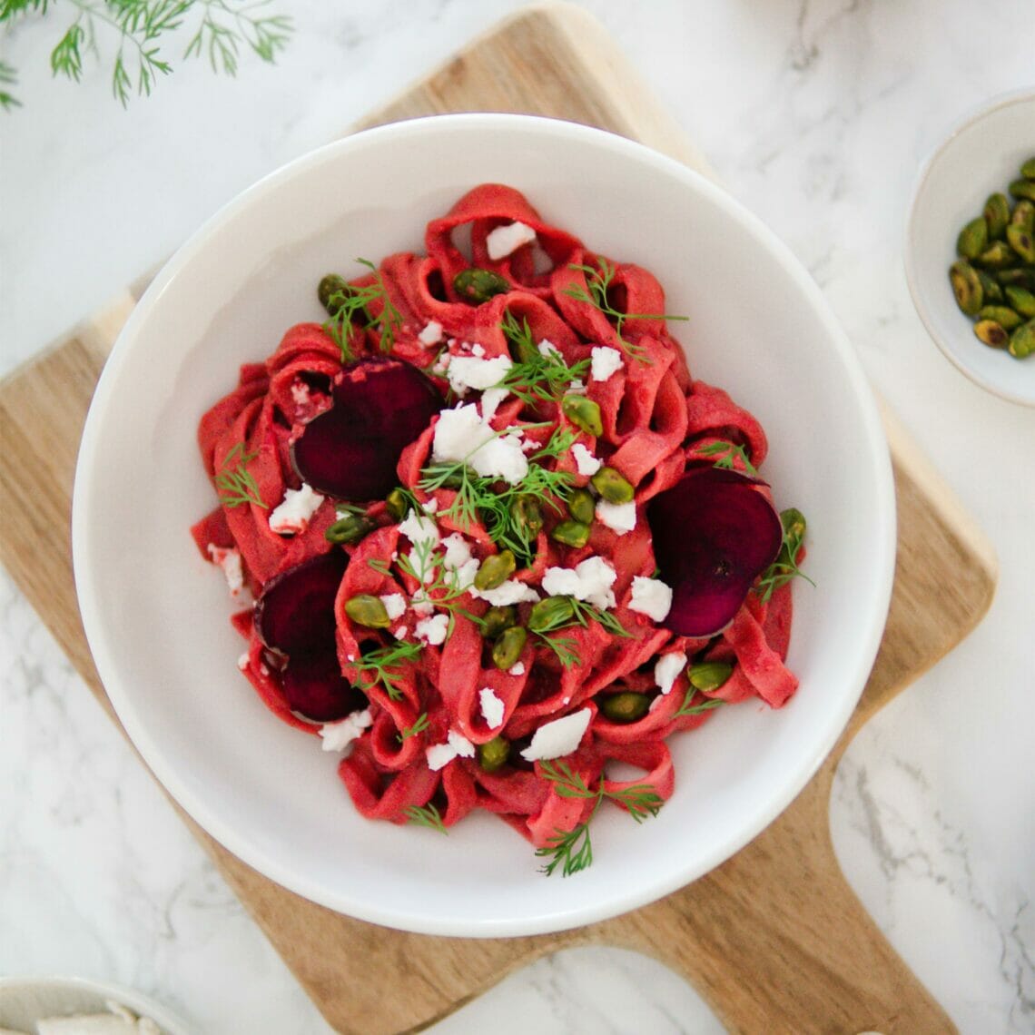 Pasta mit Rote Beete Sauce, Feta Stücken, Dill und Pistazien in einer Schale